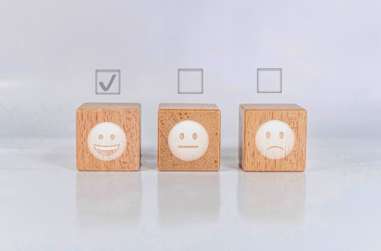 Row of building blocks with happy, meh, and sad face emojis, with check boxes above them to indicate assessment