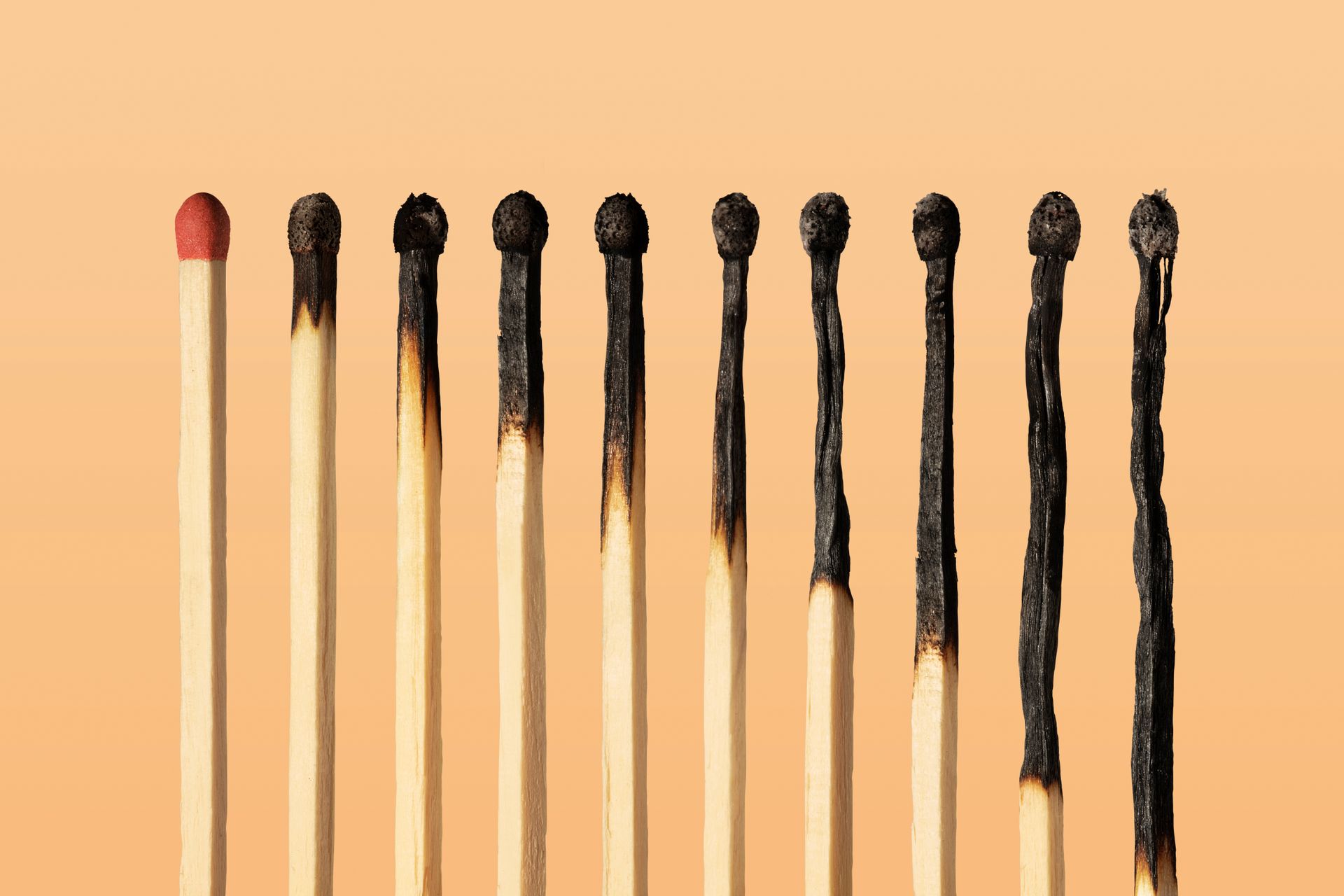 Matches against an orange background with some of them burned