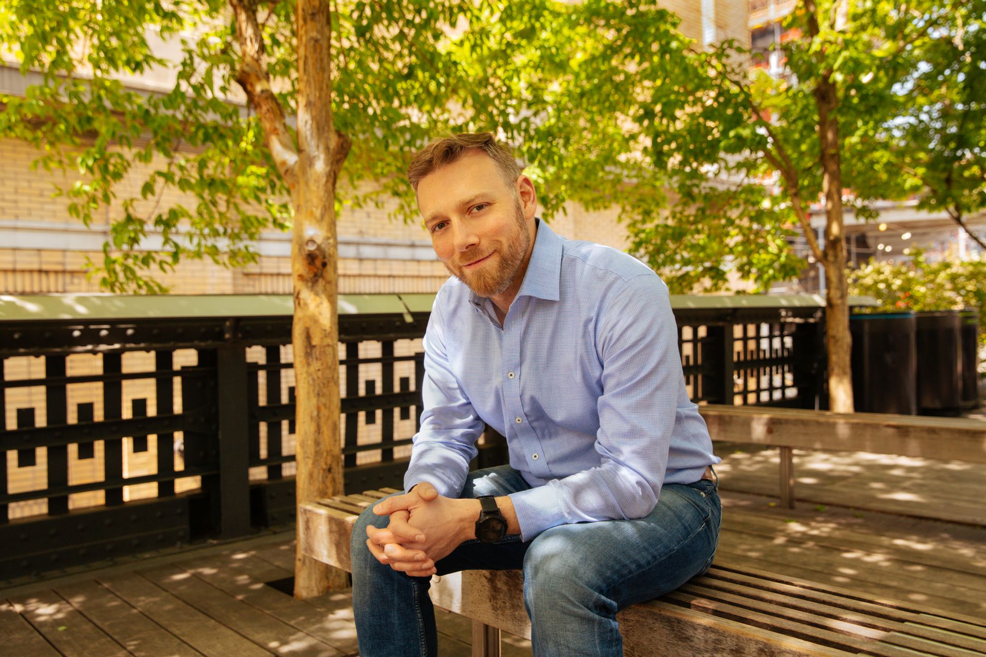 Photo of Mike Boufford sitting down on a bench in front of trees
