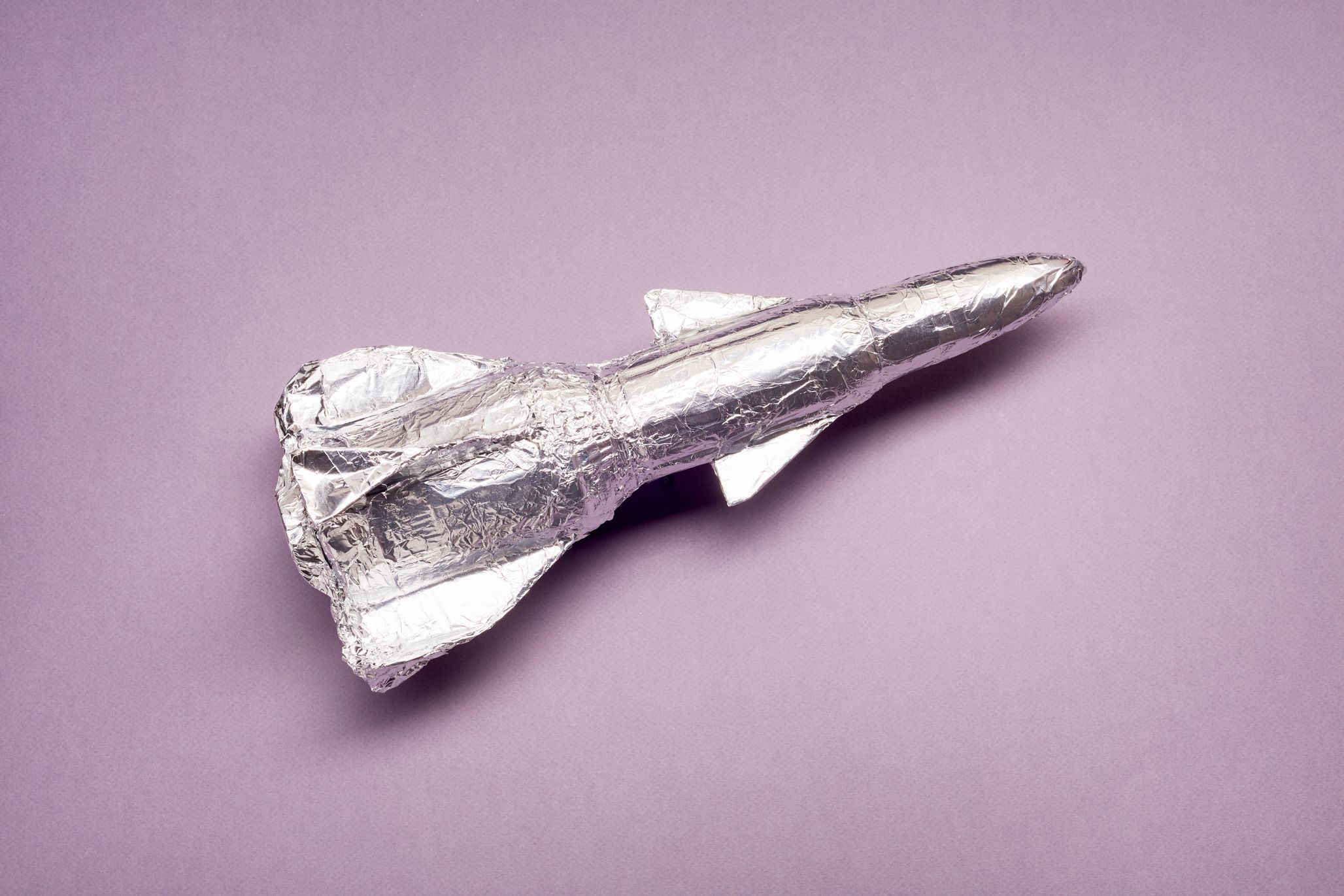 Rocketship self-made out of tinfoil, against a purple background